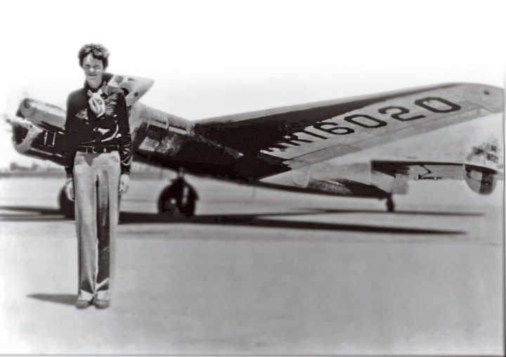 Amelia Earhart standing in front of her plane